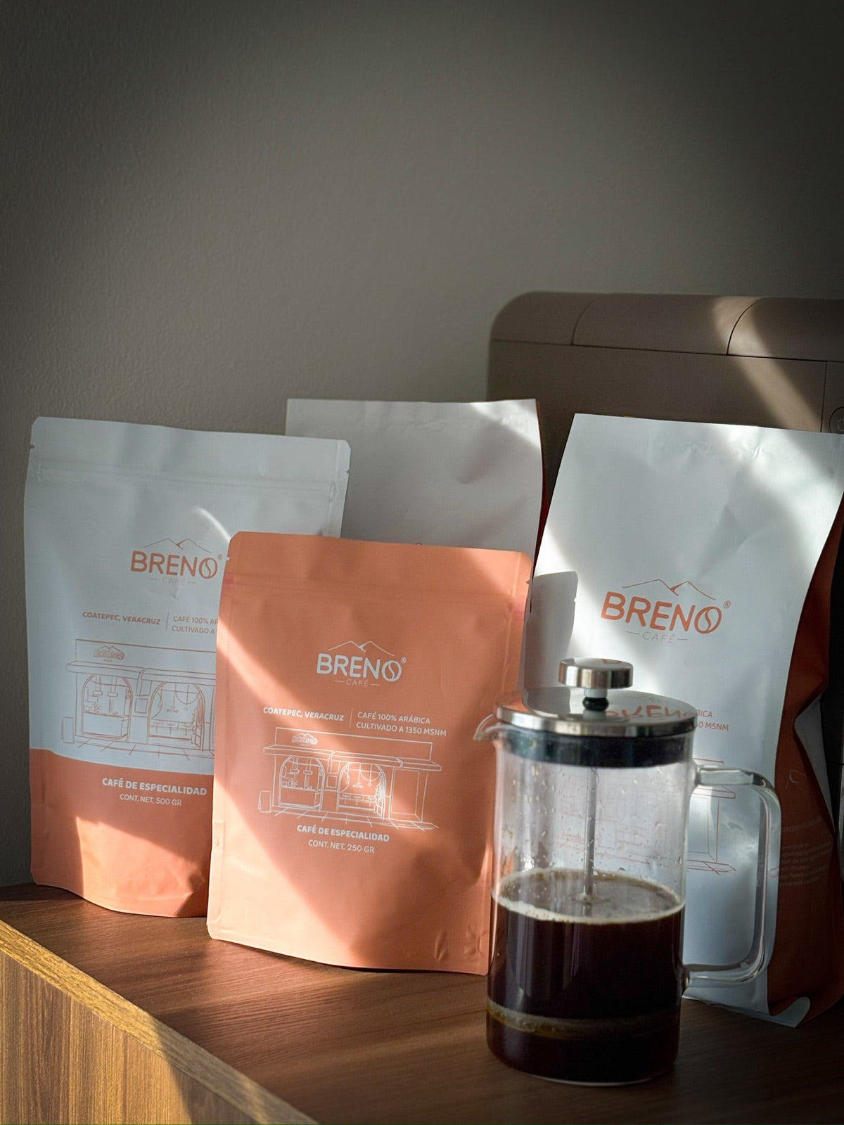 Bolsas de Café Breno de 1 kg, 500 g y 250 g junto a una prensa francesa
